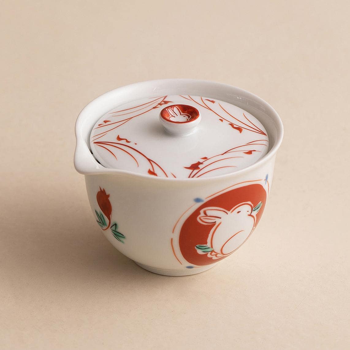 Porcelain teacup pouring tea into a matching red cup