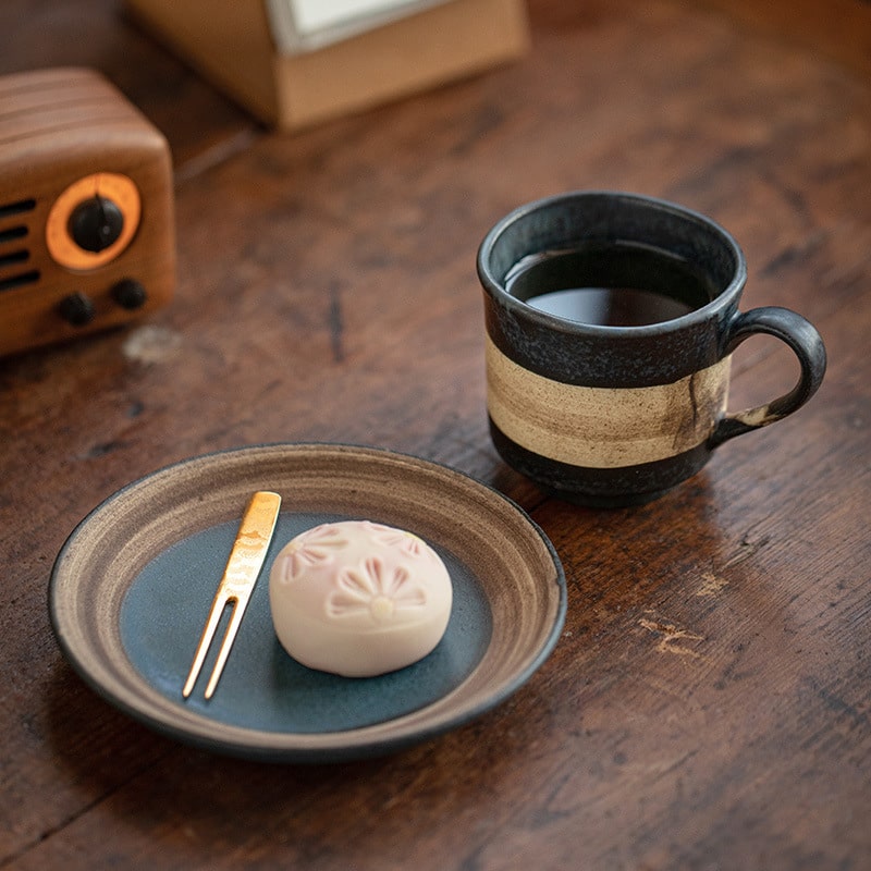 Rustic ceramic coffee mug with earthy tones on a saucer.