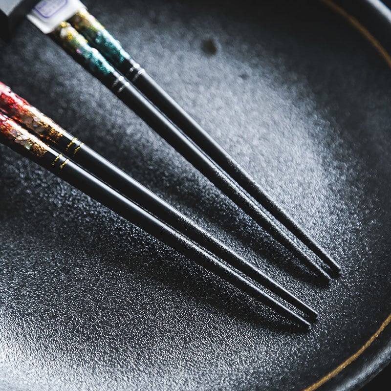 Elegant reusable chopsticks placed on a black dish.