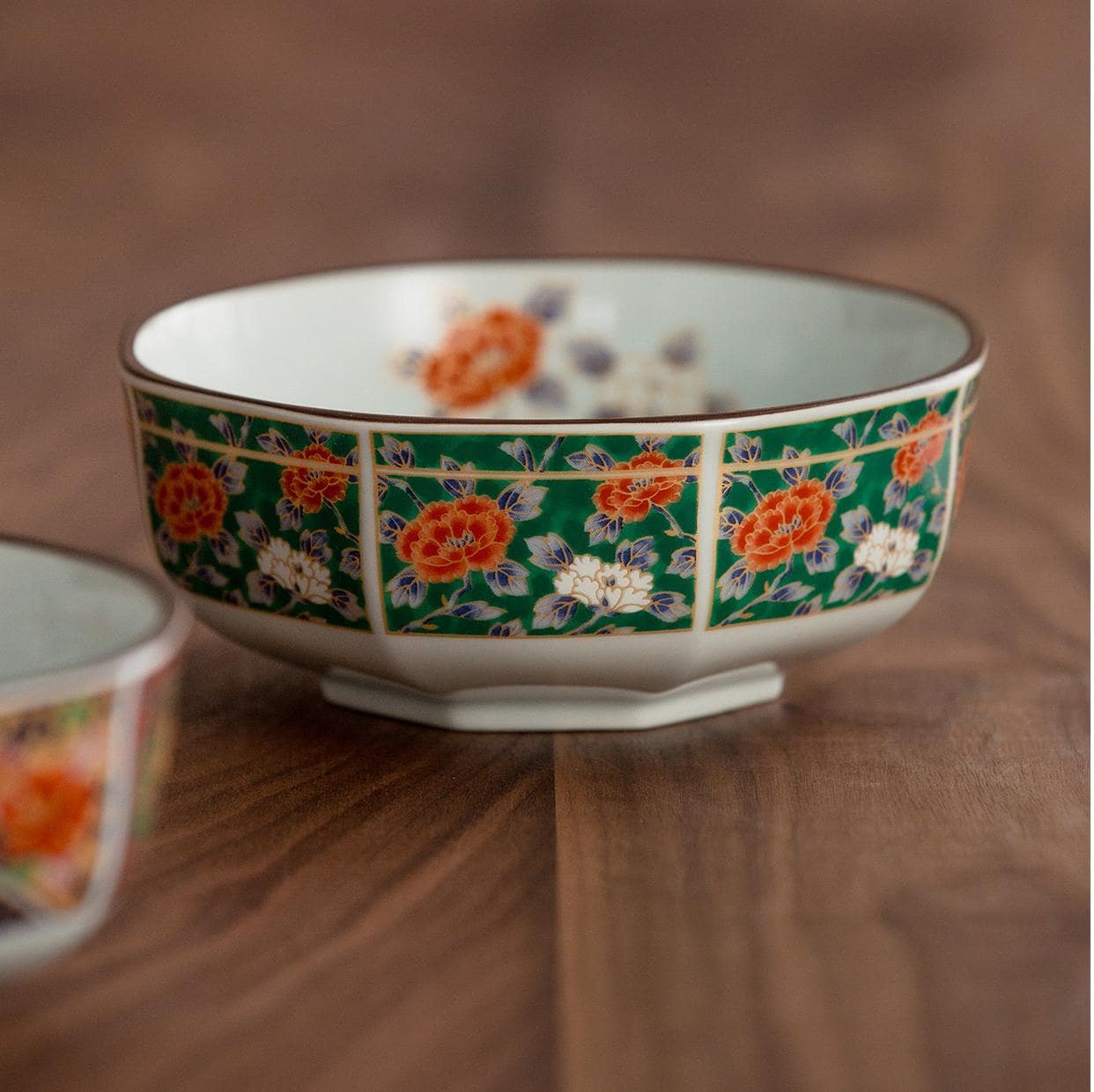 Vibrant red and gold patterned soup bowl on wooden table.