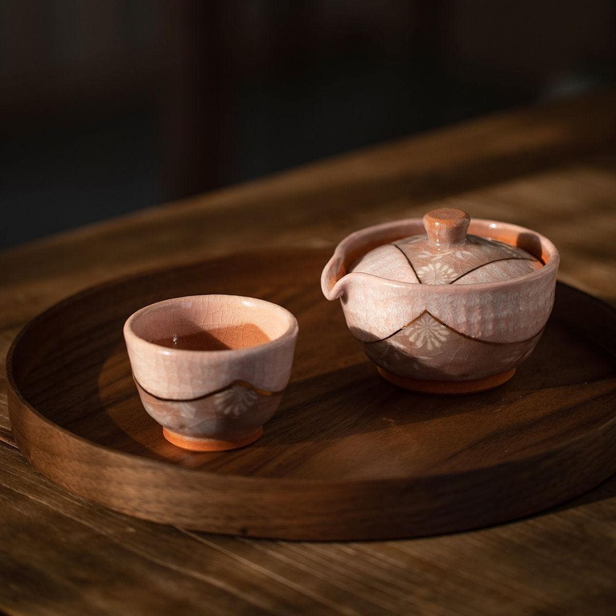 Handcrafted Japanese Kiyomizu-yaki teapot and cup on a wooden tray.