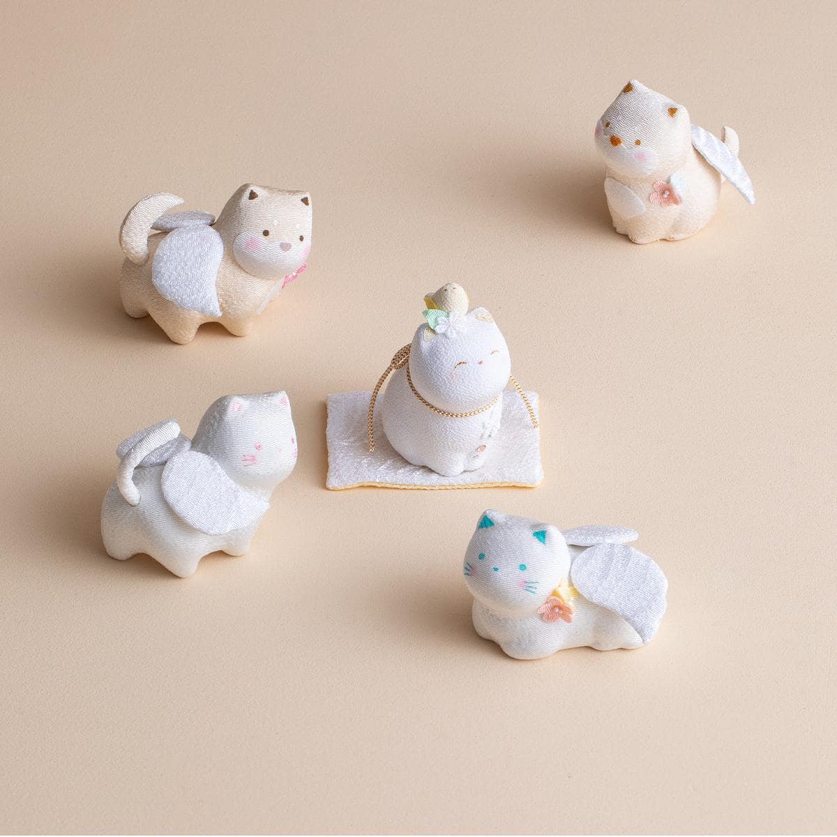 Pastel ceramic lucky cat figurines on a wooden shelf