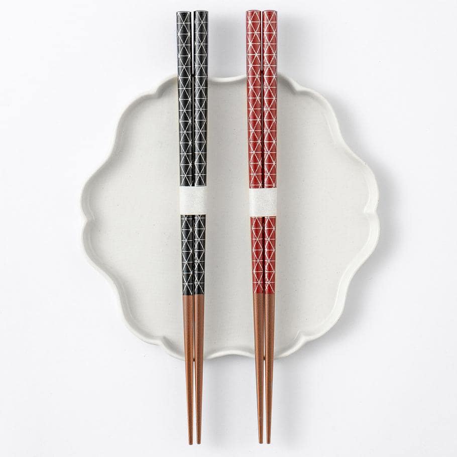 Red and black Japanese wooden star point chopsticks with geometric patterns.