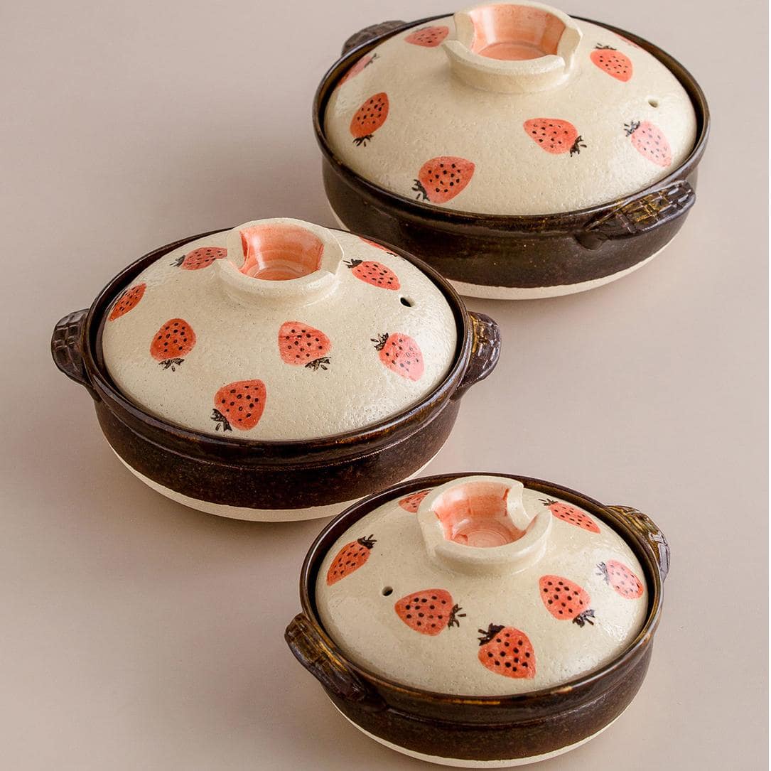 Artisan ceramic donabe pot with whimsical strawberry details.