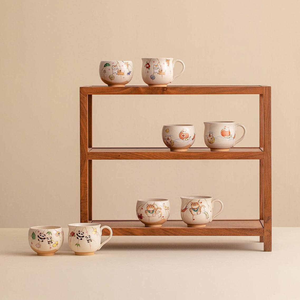 Collection of hand-painted ceramic cups with whimsical designs on a wooden shelf.