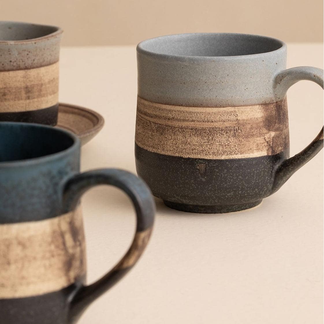 Handcrafted ceramic coffee cup with two-tone design and saucer.