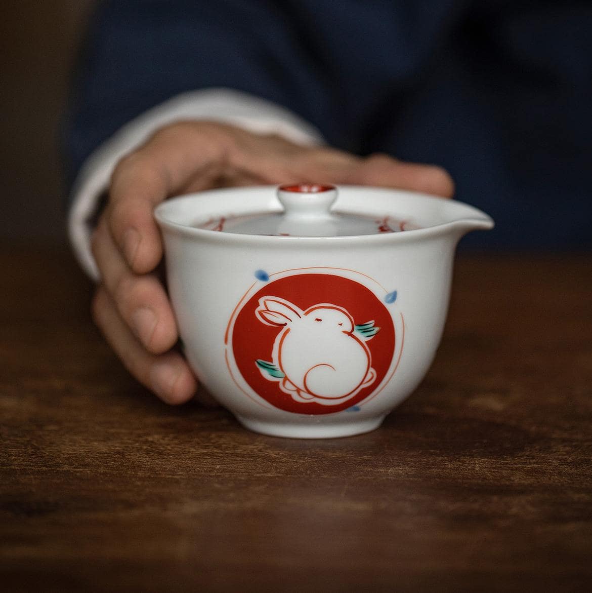 Porcelain teacup pouring tea into a matching red cup