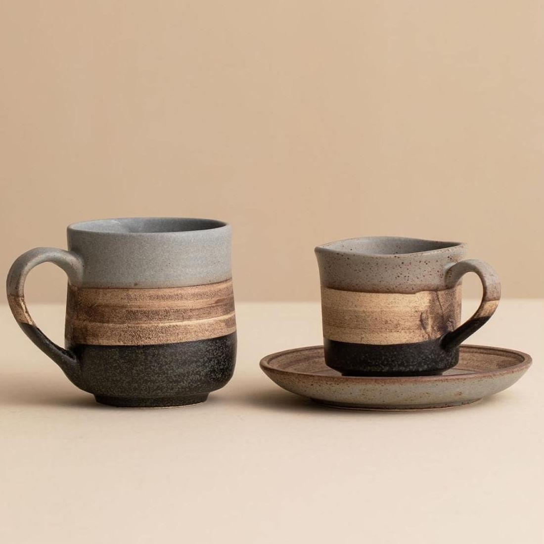 Rustic ceramic coffee mug with earthy tones on a saucer.