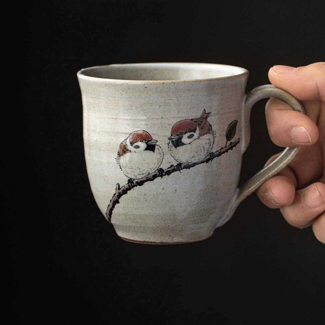 Sparrow-motif ceramic cup on a wooden table