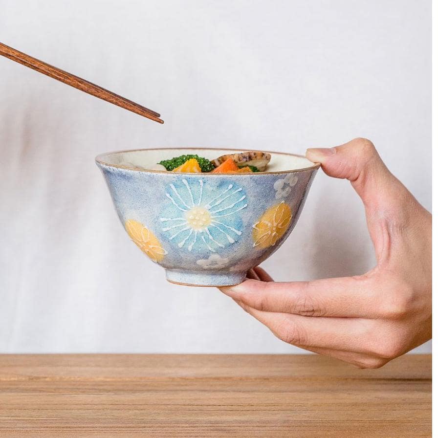 Close-up of delicate hand-painted flowers on pink and blue ceramic bowls