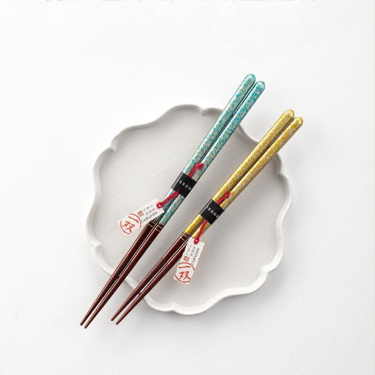 Close-up of ISHIDA Japanese wooden chopsticks with gold and turquoise patterns.