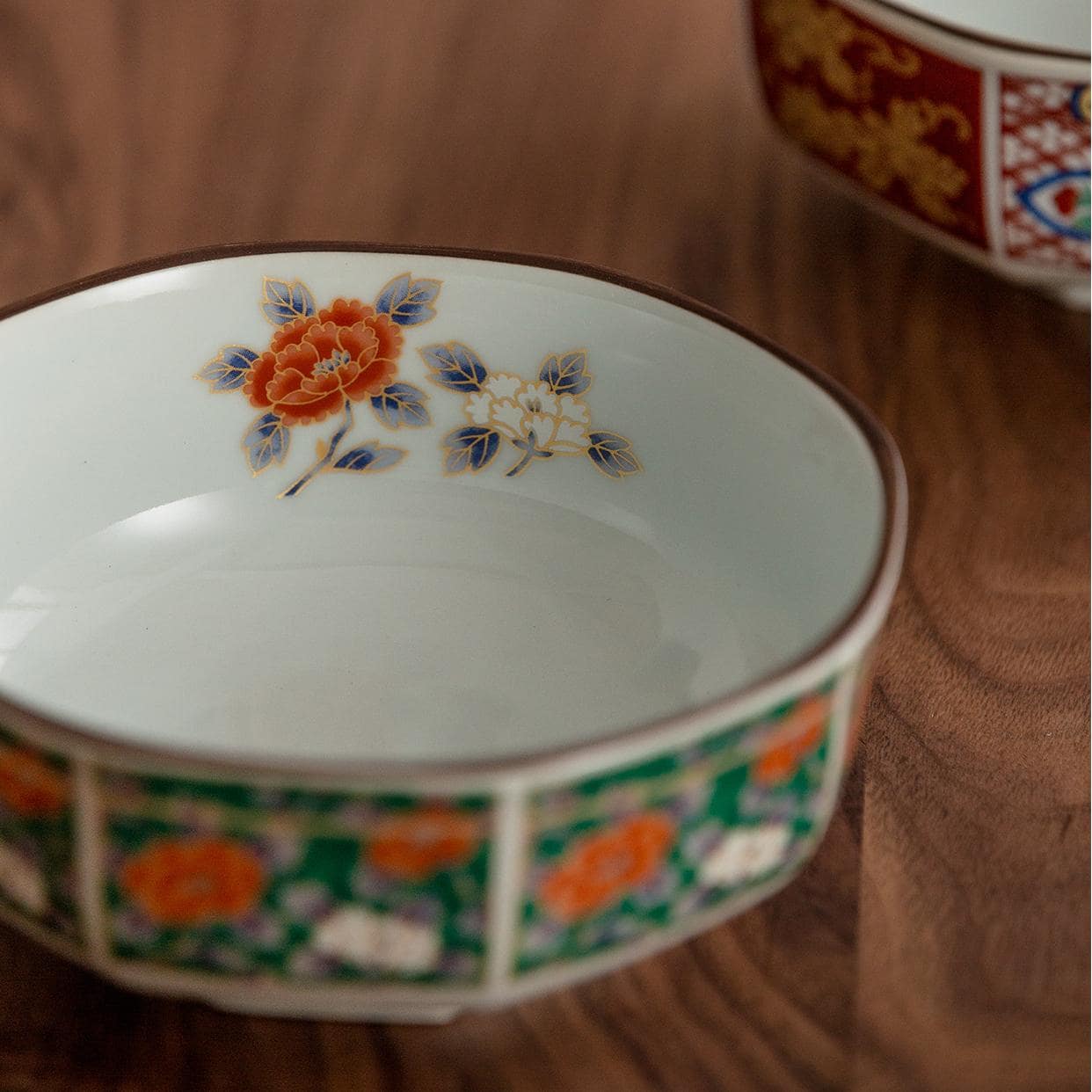 Vibrant red and gold patterned soup bowl on wooden table.