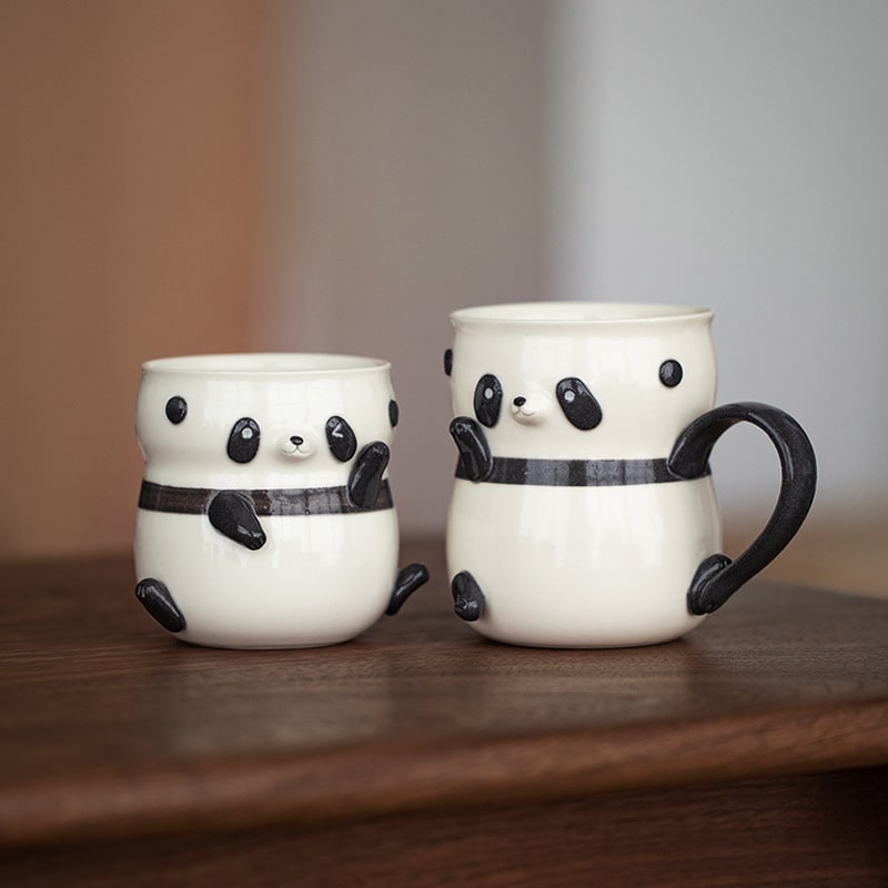 Pair of panda-shaped ceramic coffee cups on a wooden surface