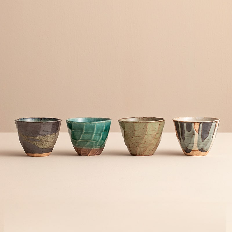 Four handcrafted Japanese ceramic cups in earthy tones