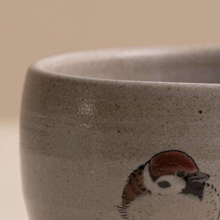 Sparrow-motif ceramic cup on a wooden table