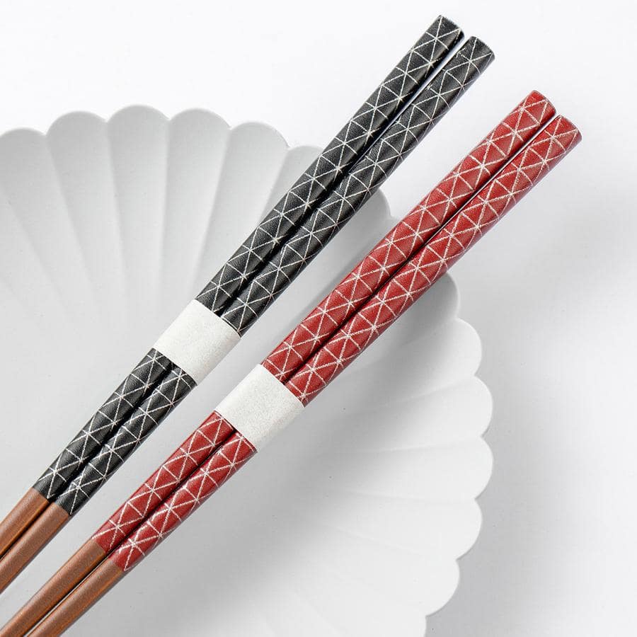 Close-up of textured non-slip star-point chopsticks in red and black.