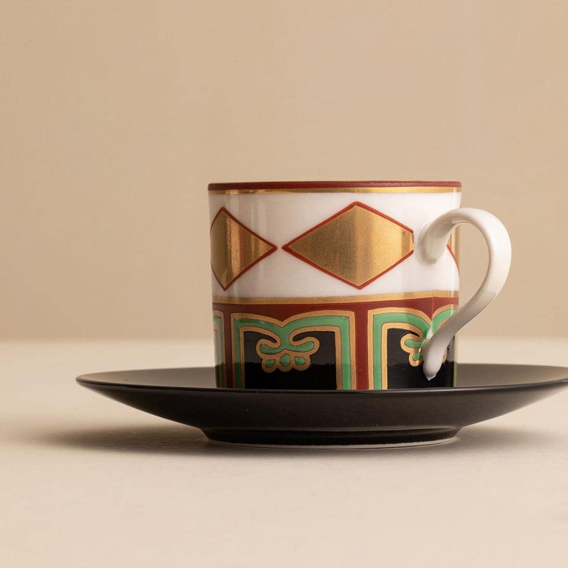 Close-up of red painted couple cups on black saucers.