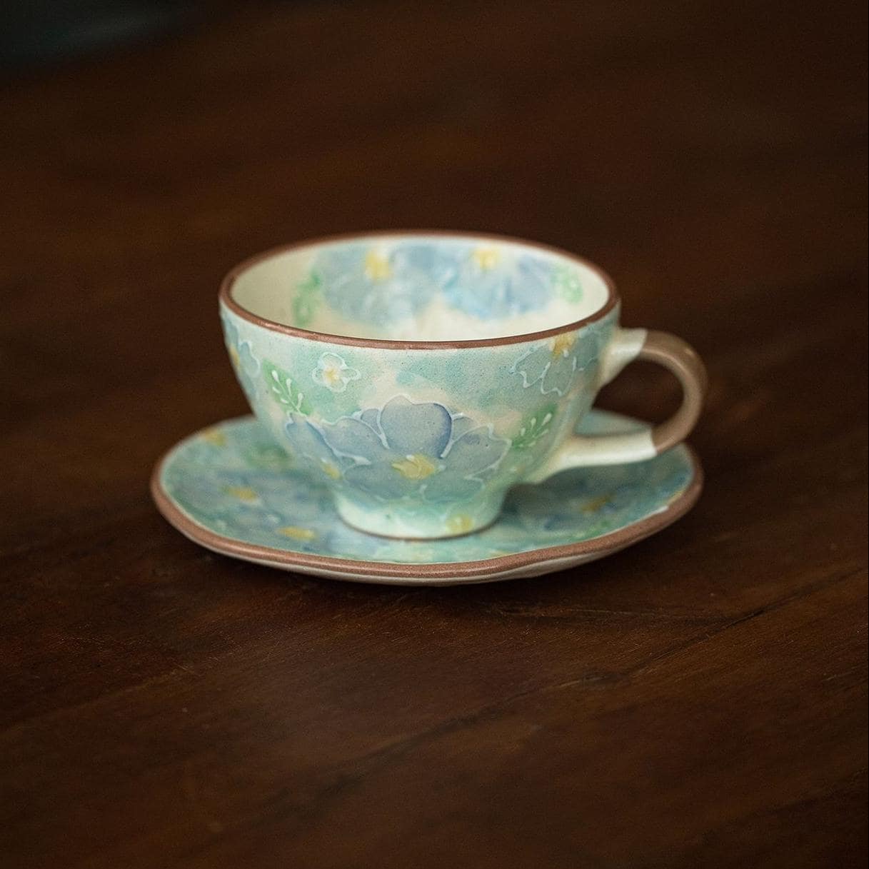 Floral ceramic tea cup filled with orange beverage