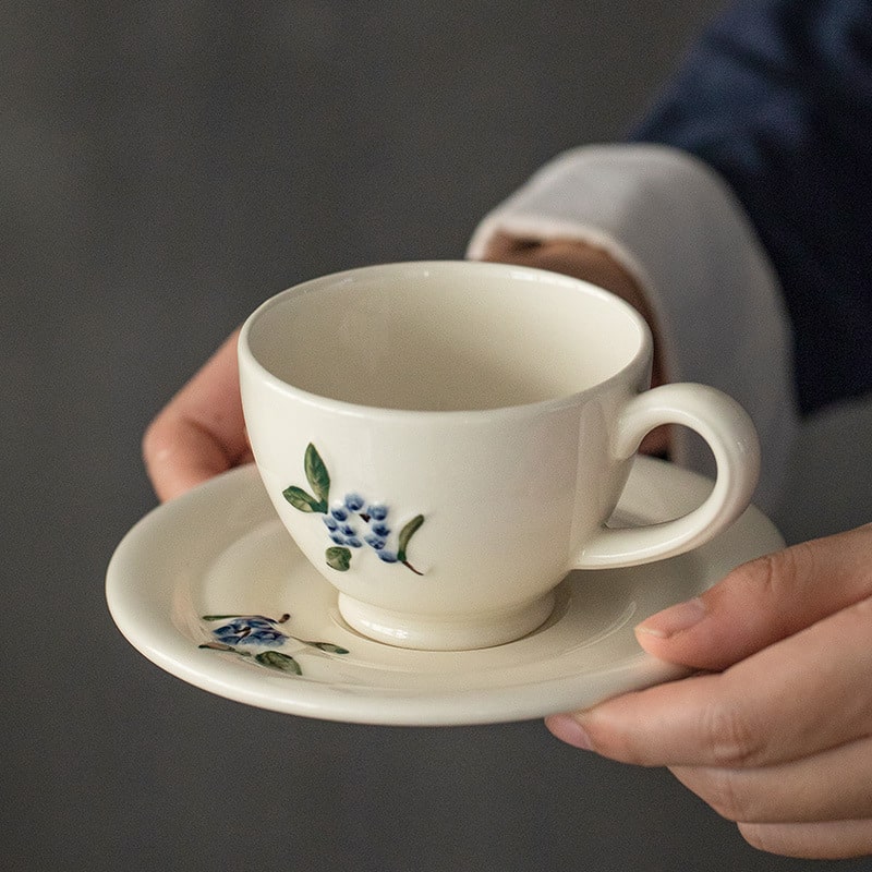 Ceramic cup and saucer set with hand-painted blueberry design.