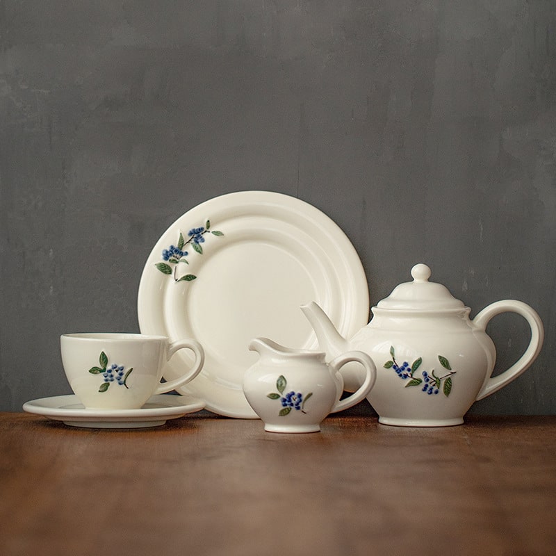 Overhead view of a blueberry-patterned tea set on a wooden table.