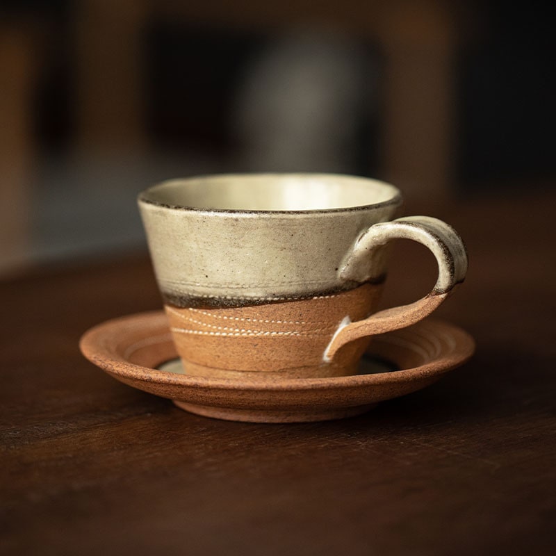 Handcrafted ceramic cup with terracotta accents and saucer.