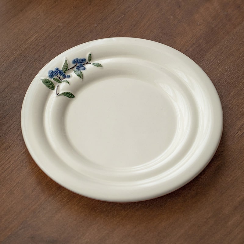 Close-up of the elegant blueberry detailing on the ceramic plate.