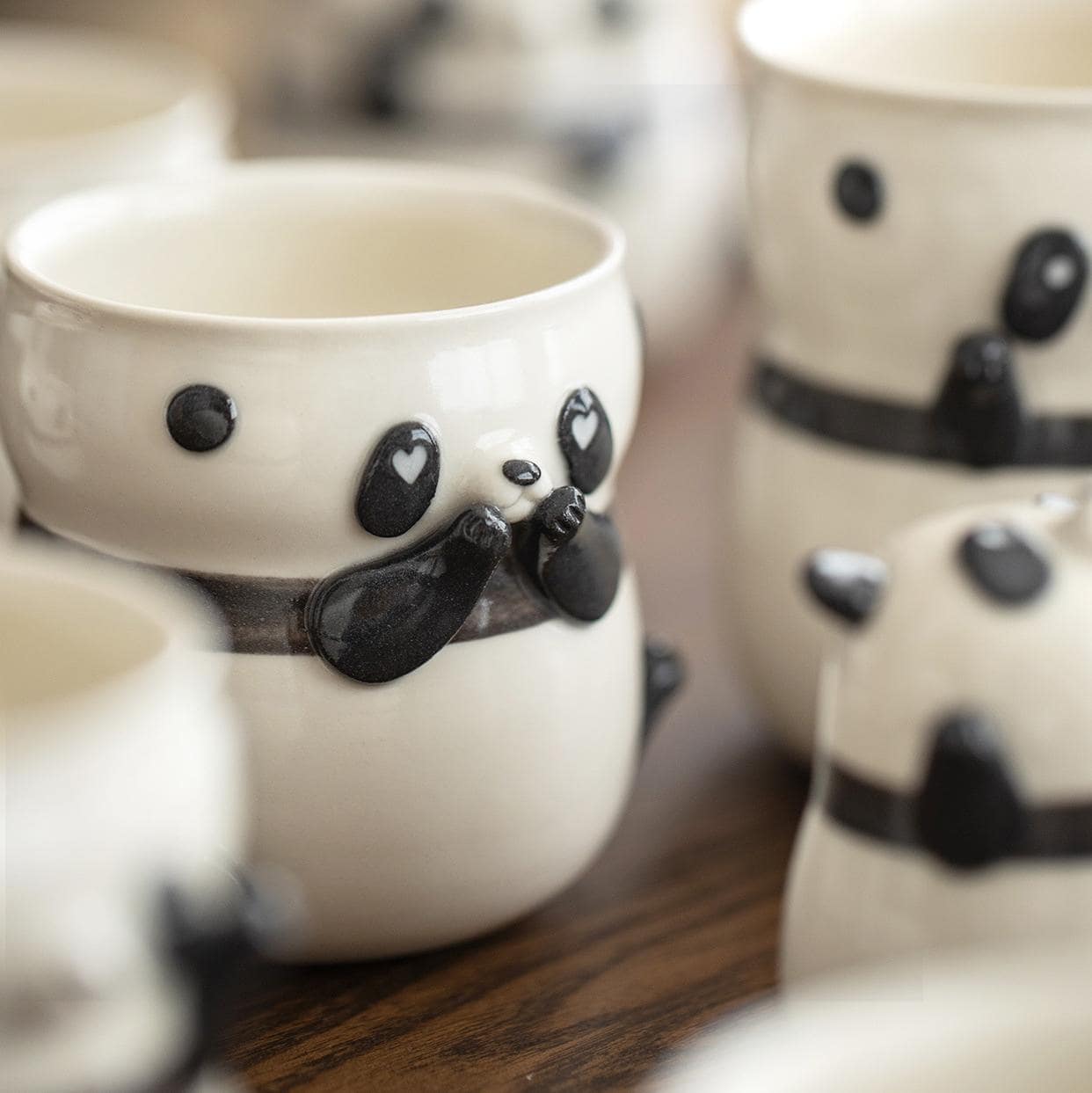 Pair of panda-shaped ceramic coffee cups on a wooden surface