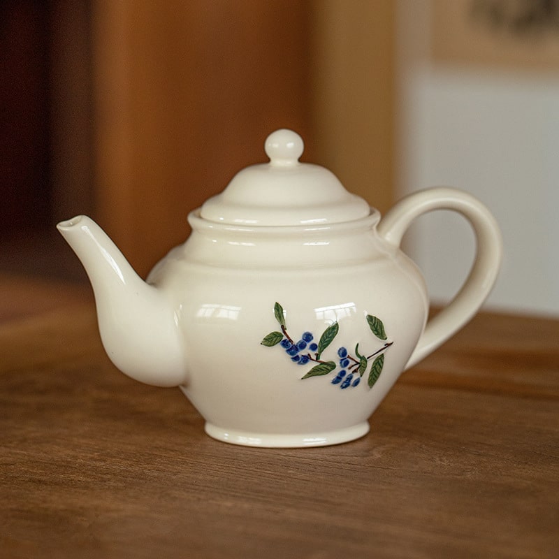 Matching teapot and ceramic cup set with botanical designs.