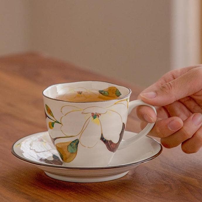 Hand holding a Japanese ceramic mug with delicate rose patterns.