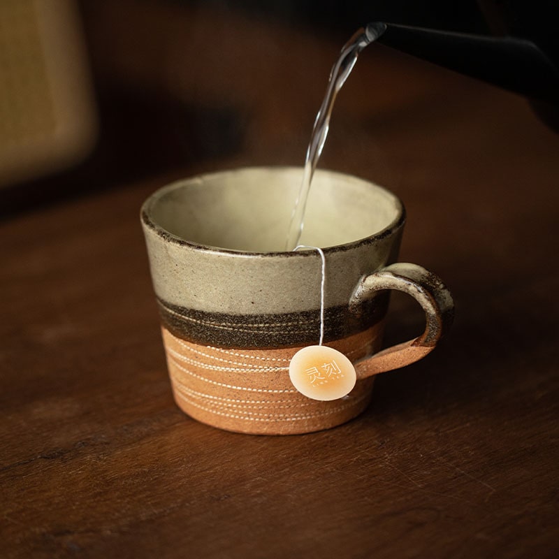 Rustic ceramic tea cup with matching saucer on a wooden table.