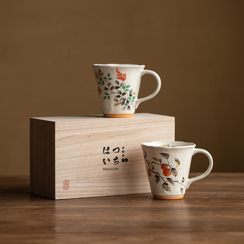 Ceramic mugs with floral patterns displayed on a wooden gift box