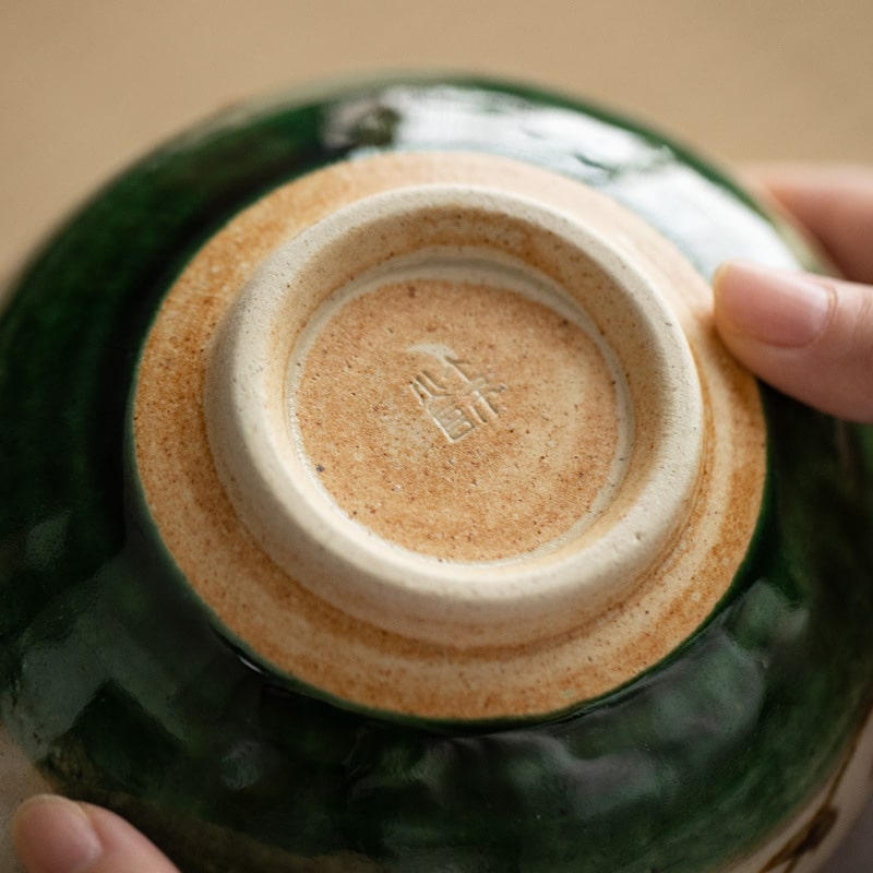 Single green ceramic bowl with floral design on wooden table