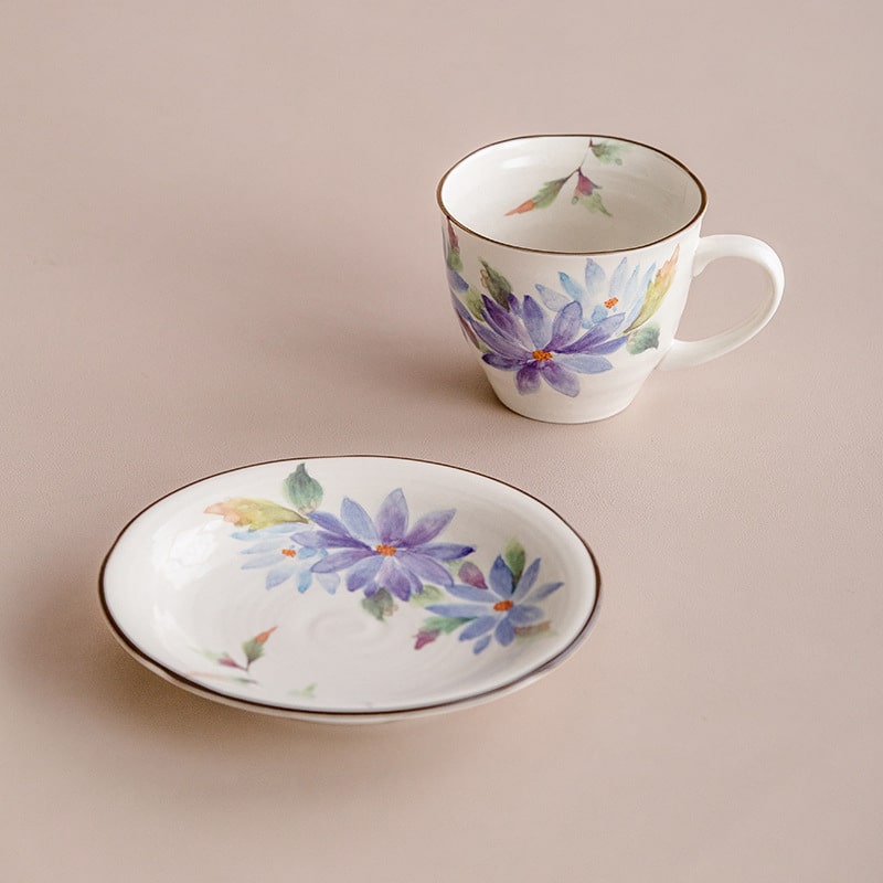 Close-up of cherry blossom and rose design on ceramic cup and saucer.