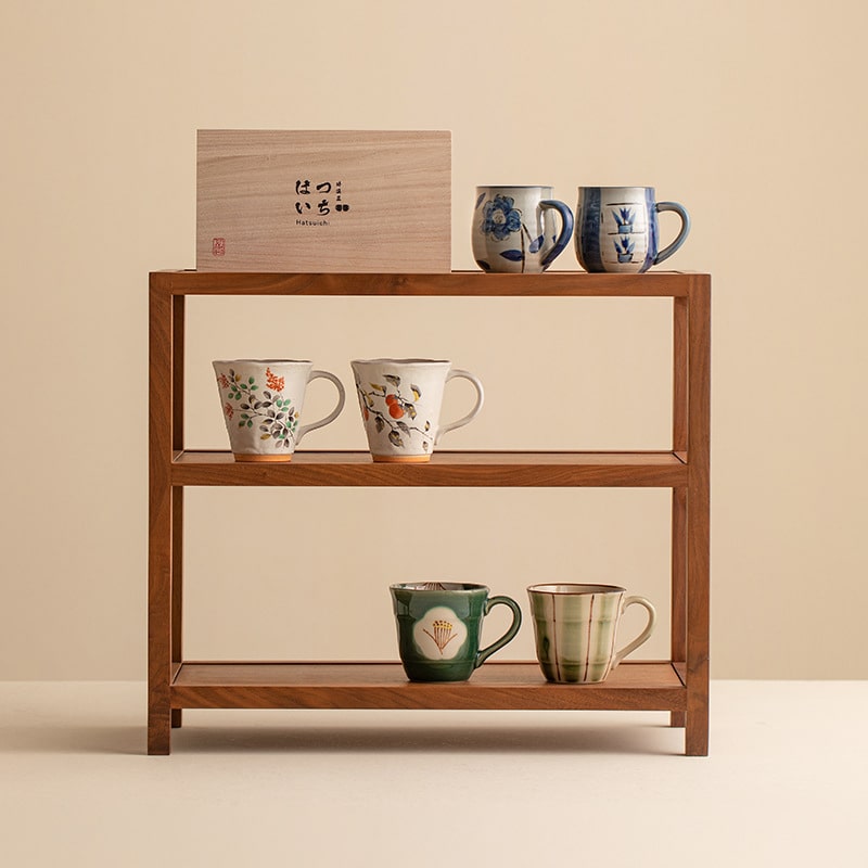 Shelf showcasing a collection of artistic ceramic mugs