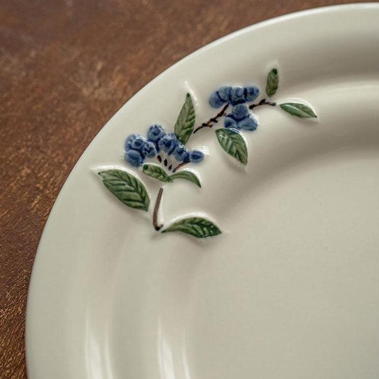 Overhead view of a blueberry-patterned tea set on a wooden table.