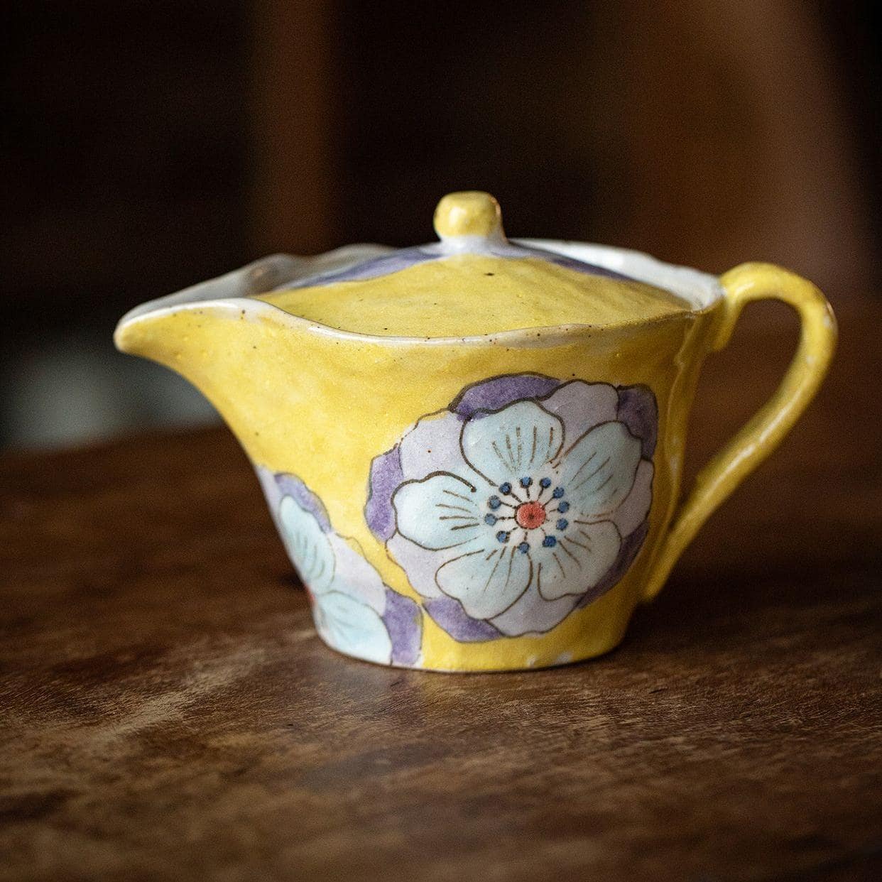 Hand-painted floral ceramic teapot on wooden table