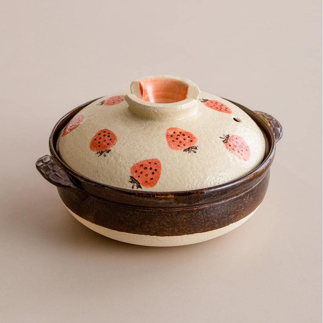 Strawberry-patterned Japanese donabe clay pot on a table.