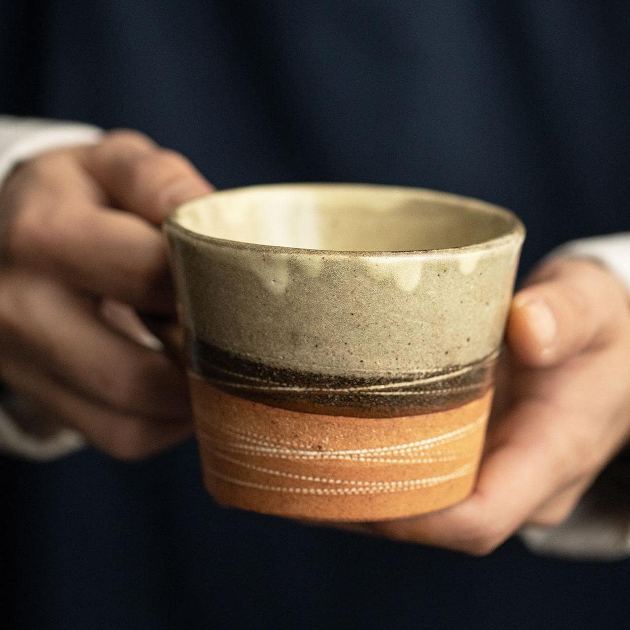 Rustic ceramic tea cup with matching saucer on a wooden table.