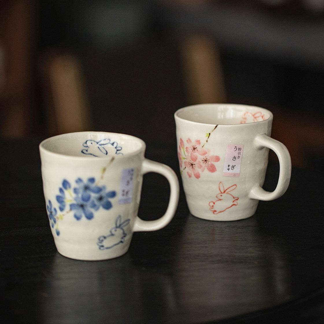 Green and striped ceramic mugs held in hands