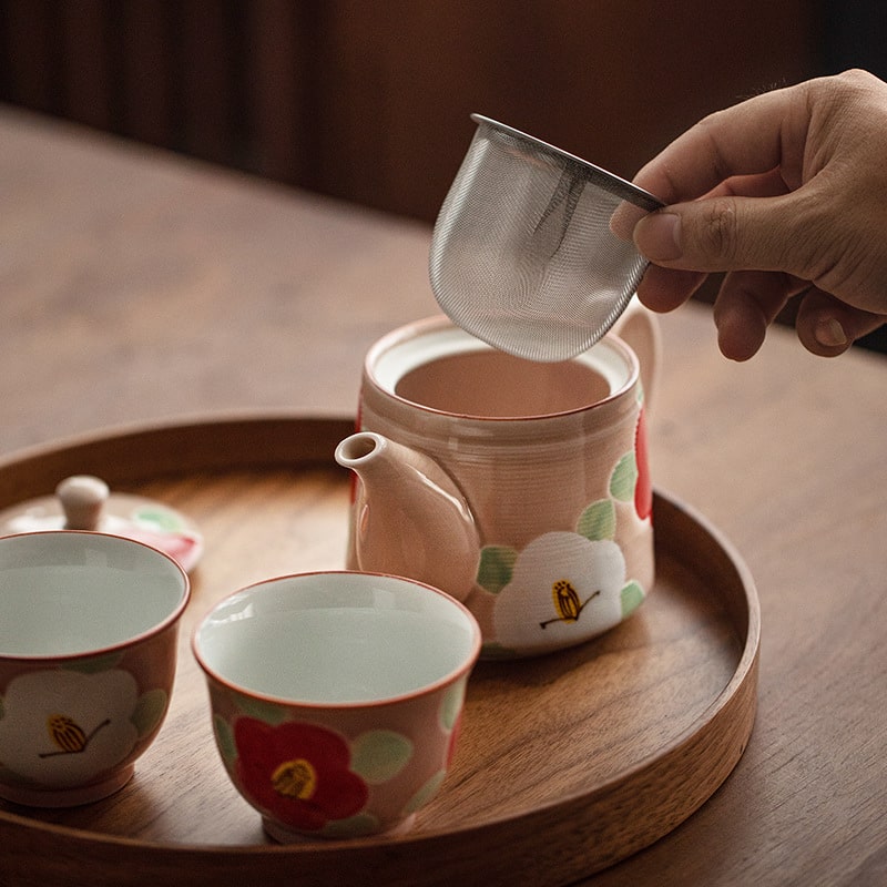 Elegant pink teapot and matching cups with floral design.