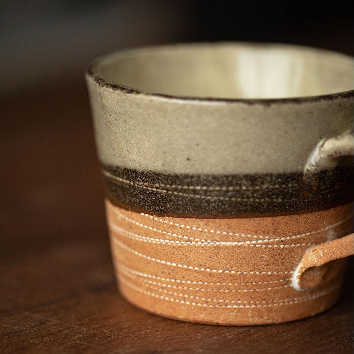 Close-up of earthy-toned coffee cup with hand-etched patterns.