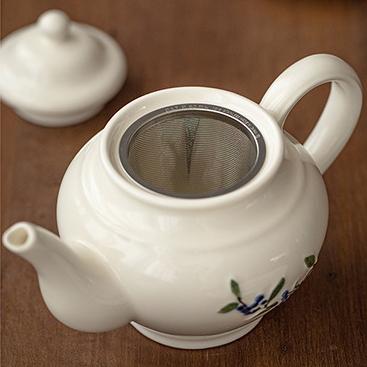 Matching teapot and ceramic cup set with botanical designs.