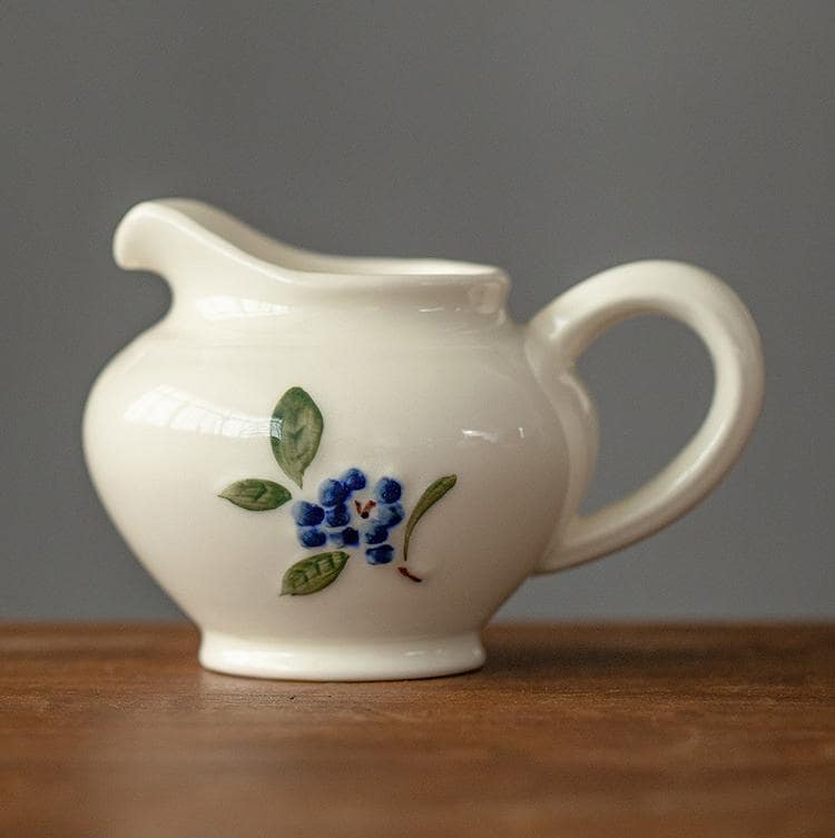 Ceramic cup and saucer set with hand-painted blueberry design.