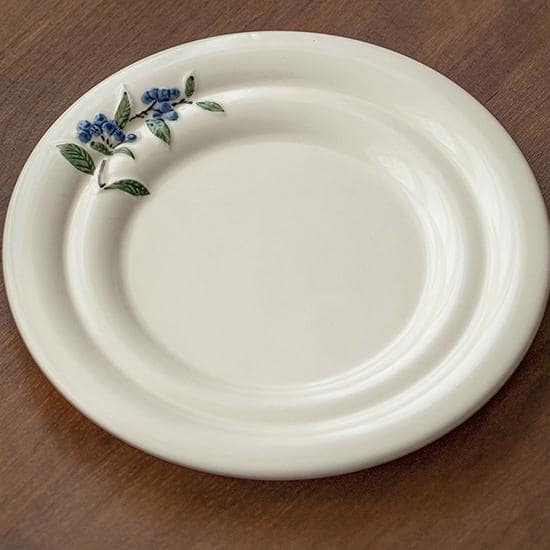 Overhead view of a blueberry-patterned tea set on a wooden table.