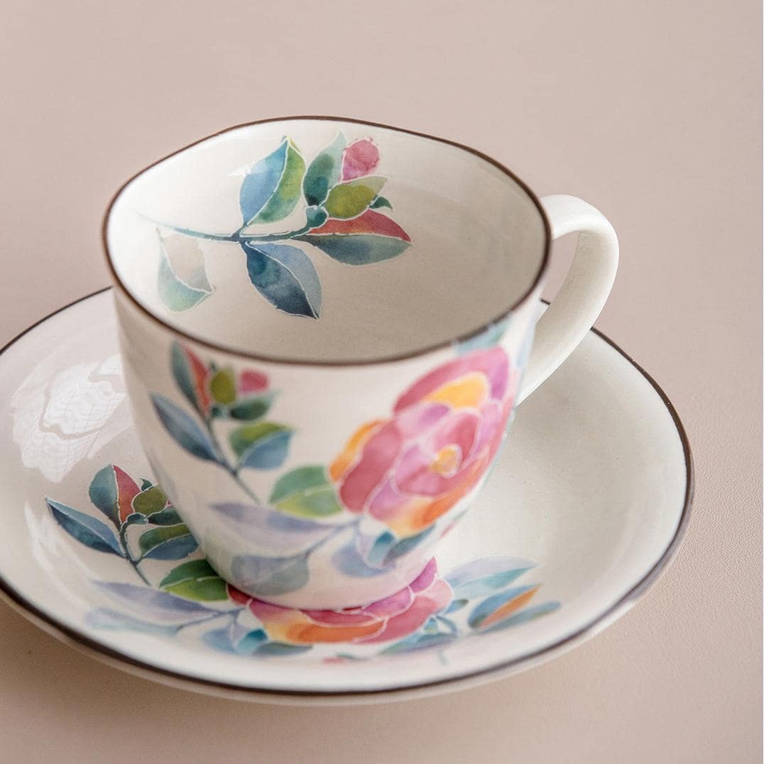 Hand holding a Japanese ceramic mug with delicate rose patterns.