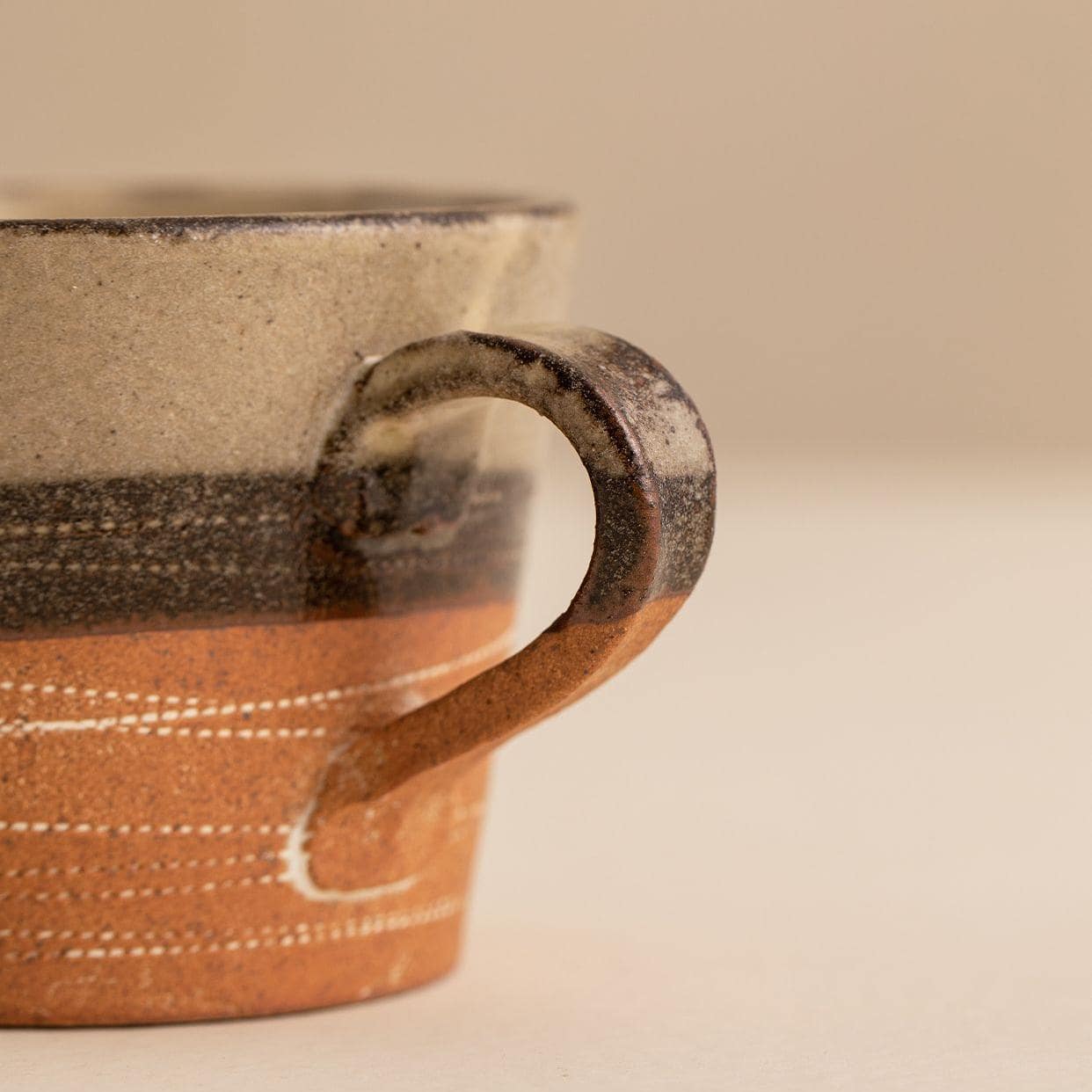 Handcrafted ceramic cup with terracotta accents and saucer.