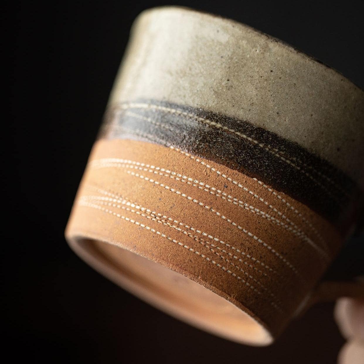 Rustic ceramic tea cup with matching saucer on a wooden table.