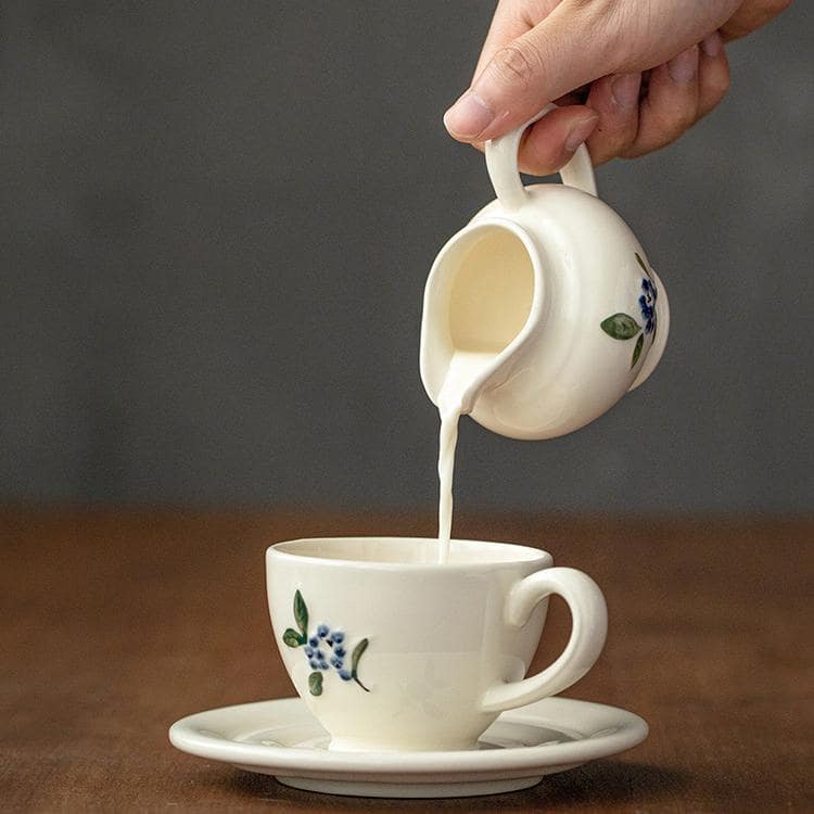 Matching teapot and ceramic cup set with botanical designs.