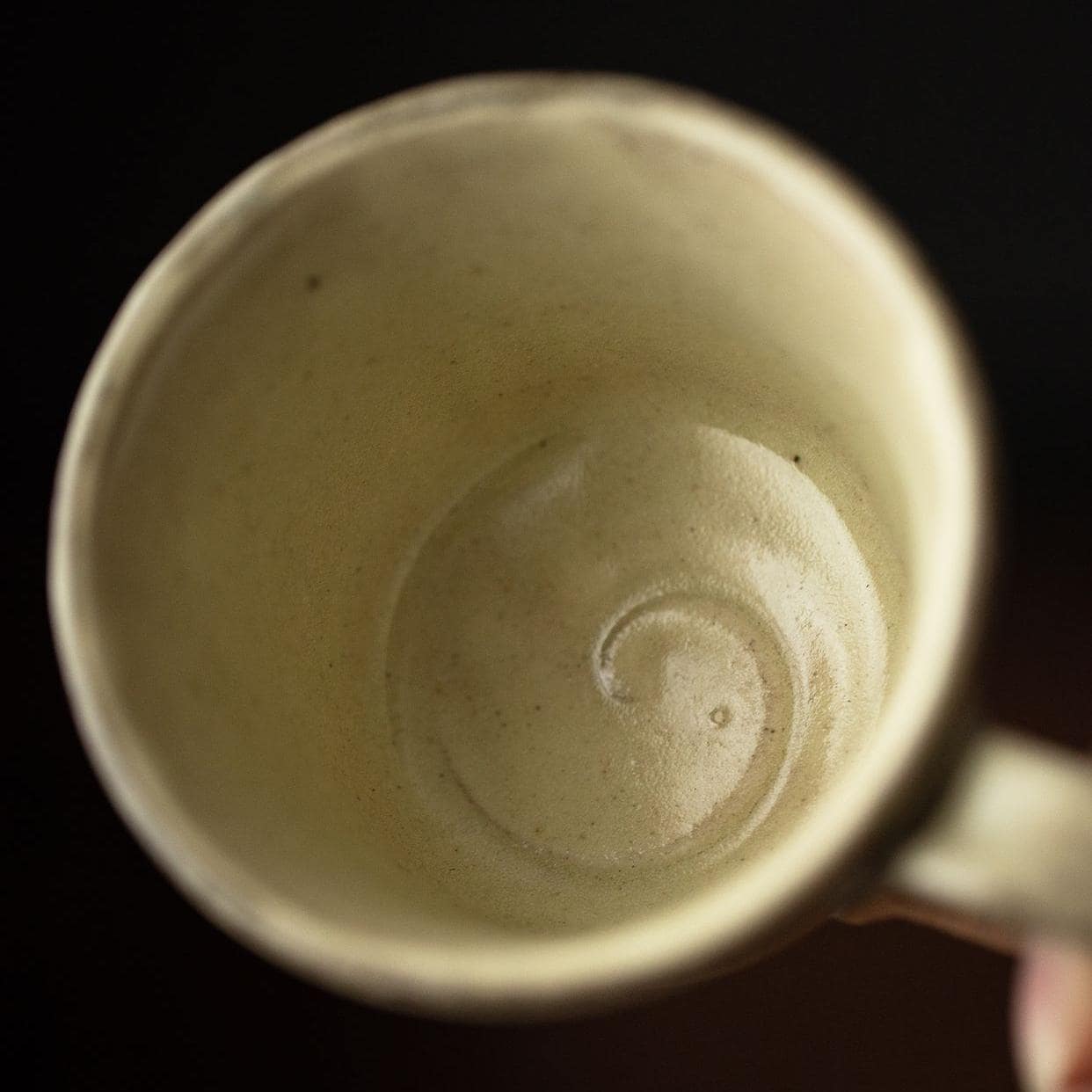 Close-up of earthy-toned coffee cup with hand-etched patterns.