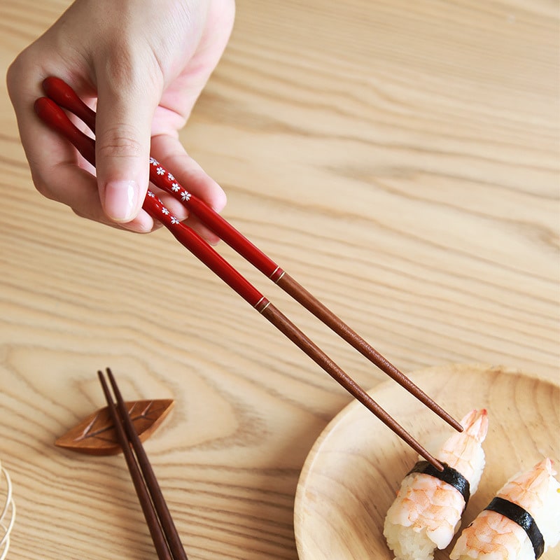 Pair of cherry blossom design chopsticks with wooden rest